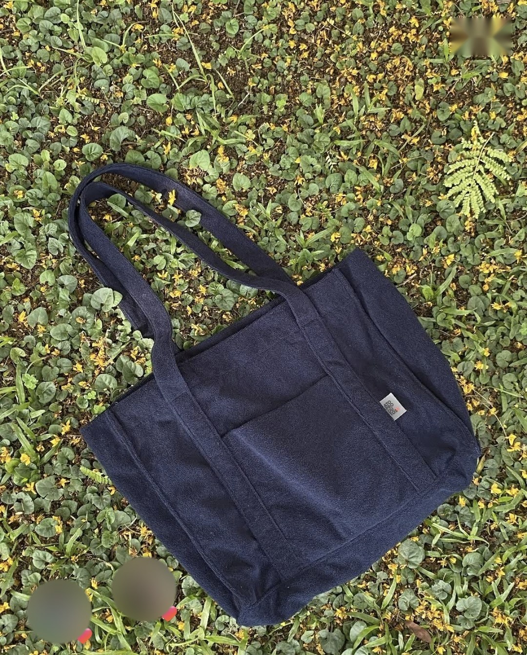 Post da ATO: bolsa atoalhada azul-marinho sobre folhagem