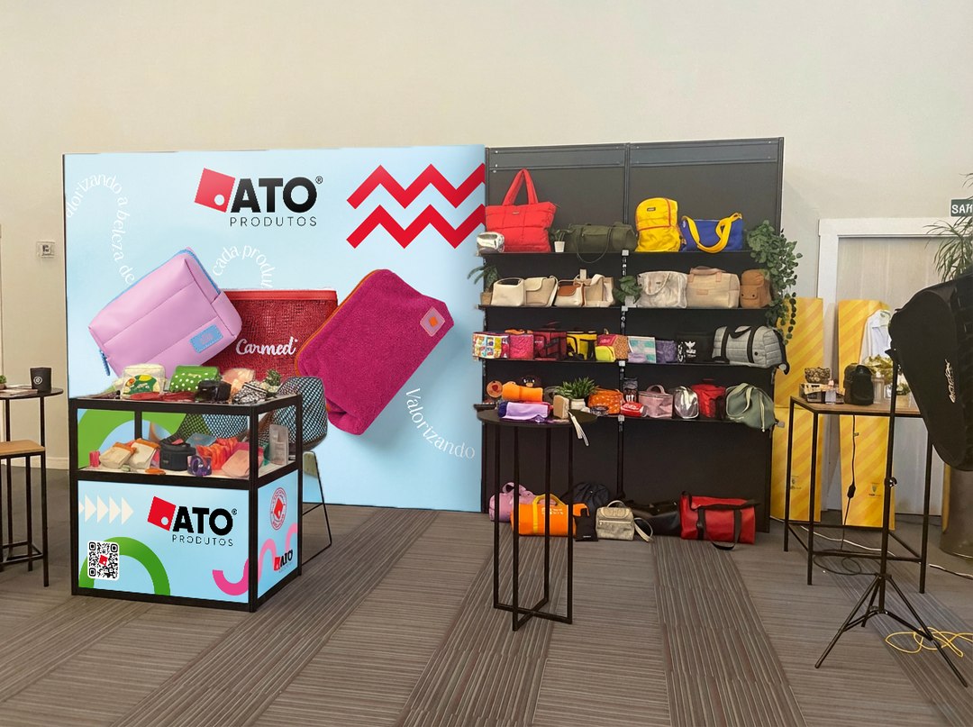 Estande da ATO montado, com painel, balcão e prateleiras de produtos