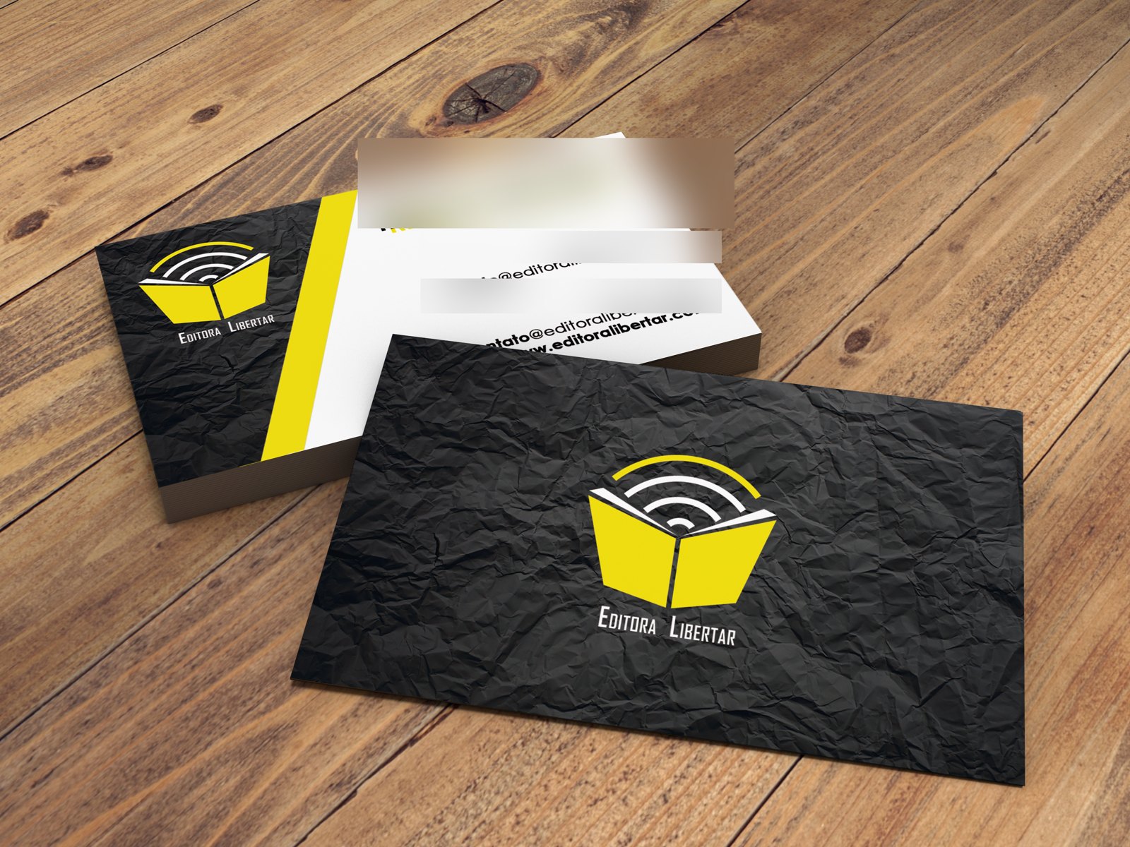 Mockup do cartão de visita Editora Libertar, frente preta com o logo amarelo e verso branco, com dados pessoais borrados